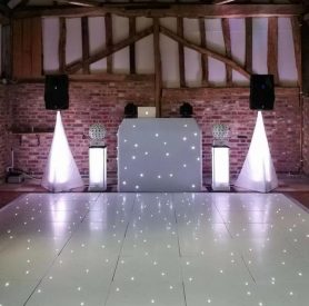 image of wedding in barn with styled backdrop, uplighting and led lit-up dancefloor
