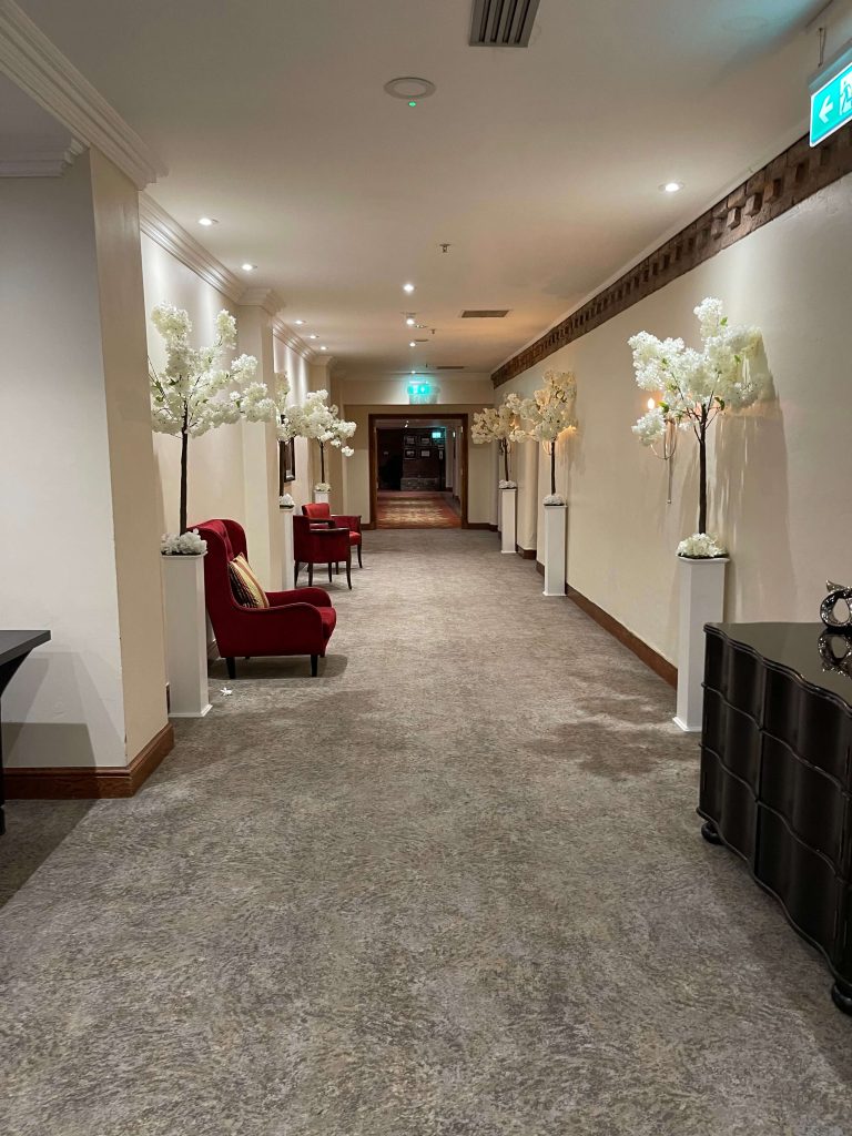 corridor in function rooms dressed with fake blossom trees for a wedding ceremony