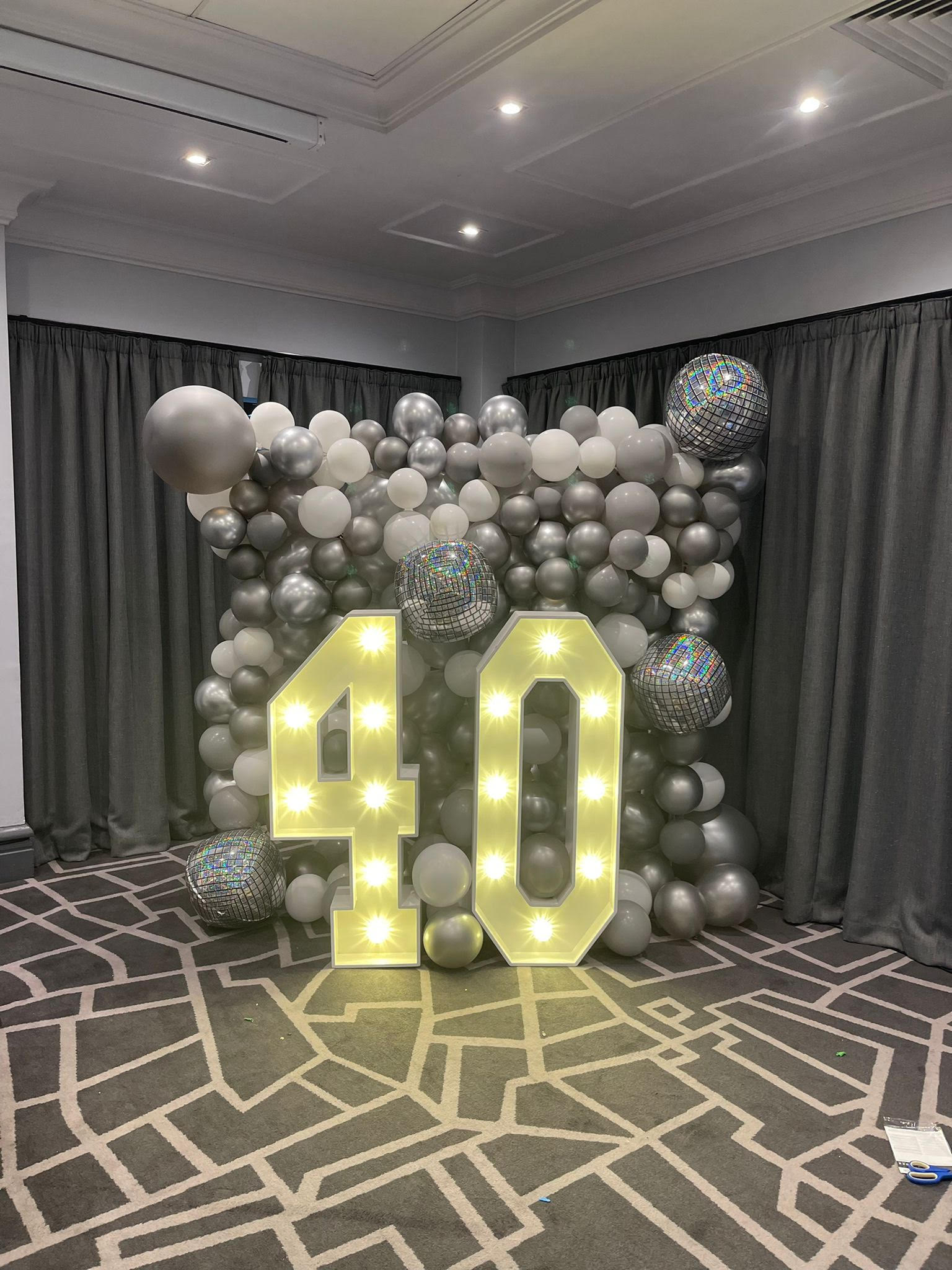 light up number 40 in front of silver and grey balloon wall for party venue